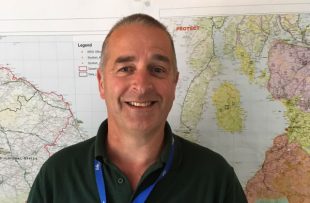 Photo of Iain Bell, APHA Veterinary Adviser in the Field Epidemiology Team, in front of some maps of Scotland