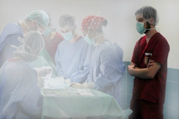 Francisco standing in an operating theatre in scrubs observing an operation