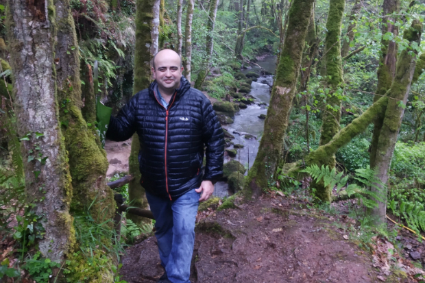 Jose standing in a wood in front of a lake